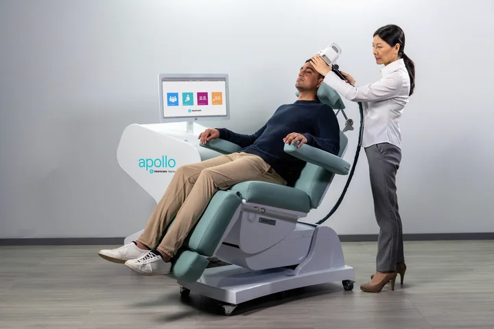 Manufacturer demonstration of a clinician positioning an Apollo coil for a seated person