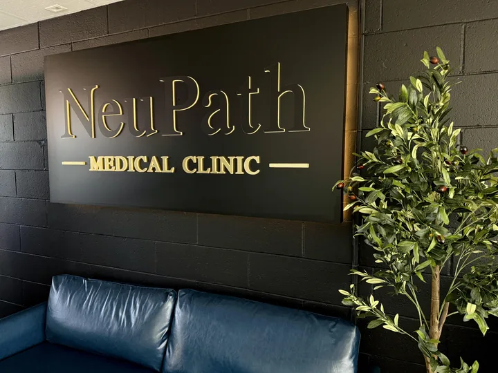 The NeuPath Medical Clinic sign above a navy sofa beside an indoor tree